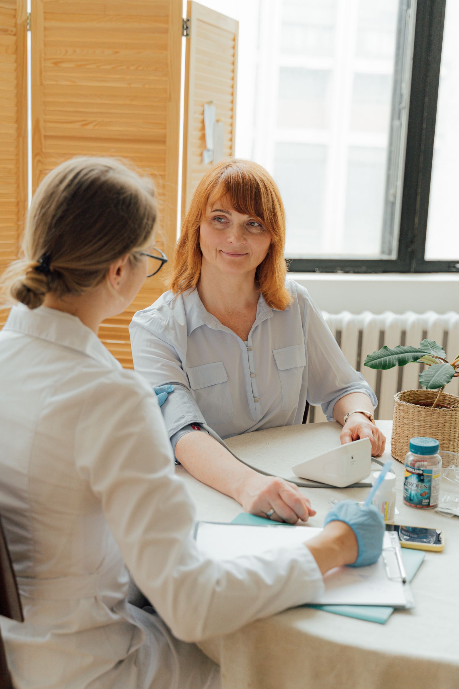 A clinician and an adult in a naturally lit consultation room, illustrative stock photograph